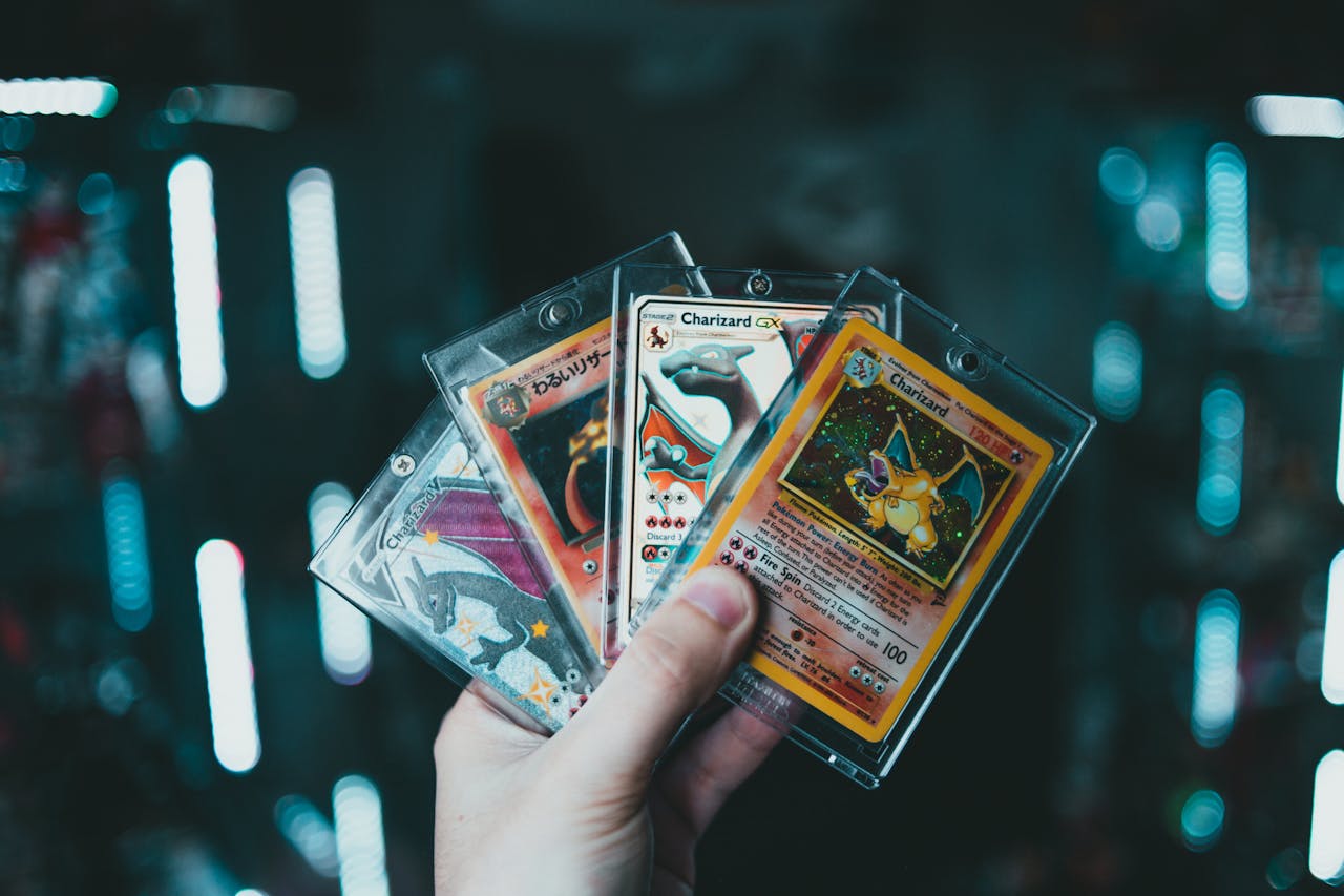 digital A hand holds collectible Charizard Pokemon cards with a blurred bokeh background. Perfect for trading card enthusiasts.